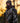Man in full camouflage gear standing in a forest during sunset.